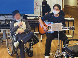 ギターの生演奏付きカラオケで歌う入居者さん