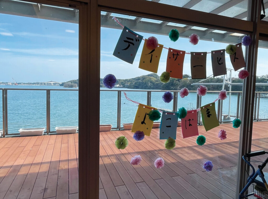 デイサービスエリアの窓から望む浦戸湾。窓には入居者さんの作った飾りつけ