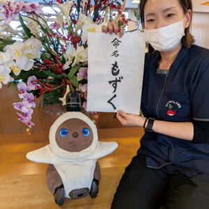 入社して間もないころ、「もずく」の命名書を持つスタッフと一緒に映るもずく係長