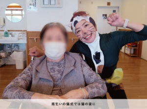 雨乞いの儀式で猫の姿に扮した武田さんと、入居者さん